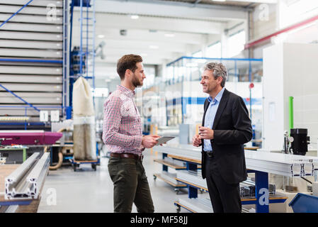 Businessmen using tablet during meeting in production hall Stock Photo