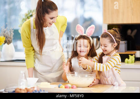 Happy mother and daughters baking Easter cookies in kitchen together Stock Photo