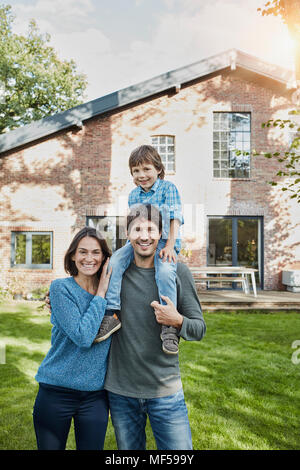 Portrait of happy family with son in garden of their home Stock Photo