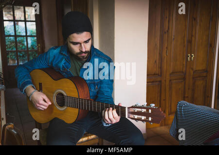 Young man at home playing guitar Stock Photo