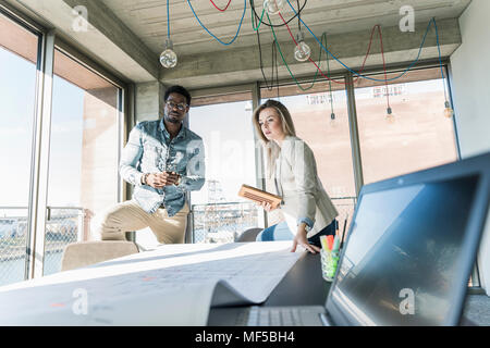 Two colleagues working on plan at table in office Stock Photo