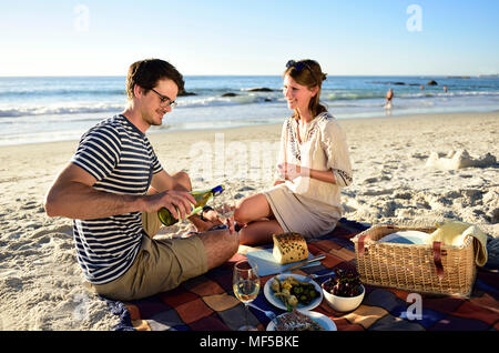 Happy couple having a picnic on the beach Stock Photo