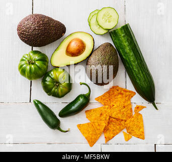 Sliced and whole avocado, green tomatoes, Jalapeno peppers, cucumber and tortilla chips Stock Photo