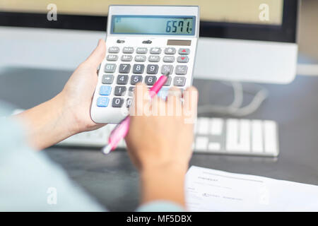 Woman at desk in office using calculator Stock Photo