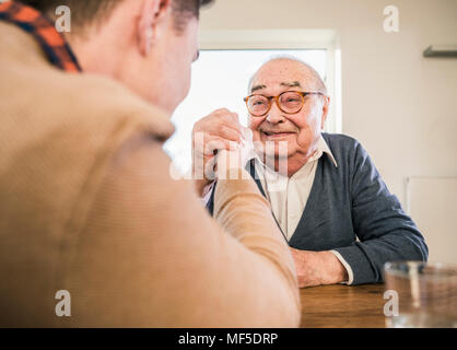 Smiling senior man arm wrestling with young man Stock Photo