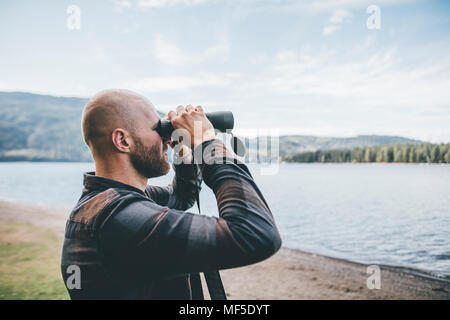 Canada, British Columbia, man looking through binoculars at Cultus Lake Stock Photo