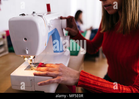 Fashion designer in studio using sewing machine Stock Photo