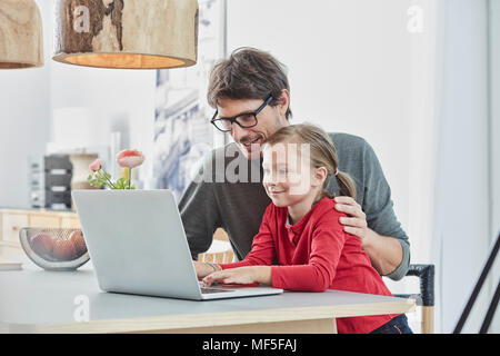Smiling father and daughter using laptop on table at home Stock Photo