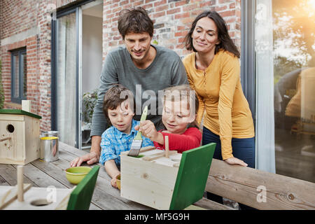 Family working on birdhouse in front of their home Stock Photo