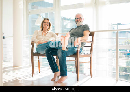 Portrait of relaxed mature couple sitting on chairs at home Stock Photo
