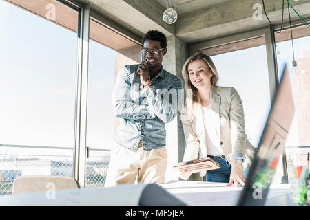 Two colleagues working on plan at table in office Stock Photo