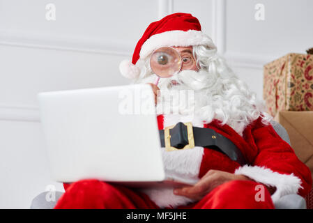 Santa claus using laptop with magnifier Stock Photo