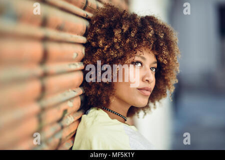 Spain, Andalusia, Malaga. Young black woman, afro hairstyle looking away in urban street wearing casual clothes. Youth urban Lifestyle. Stock Photo
