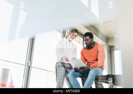 Casual businesswoman and businessman discussing papers in office Stock Photo