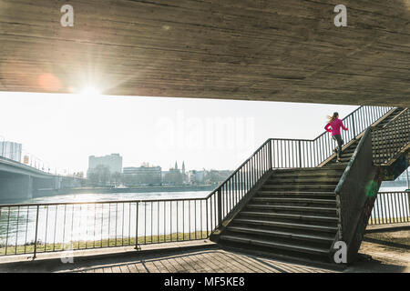 Young woman running up stairs at a river Stock Photo