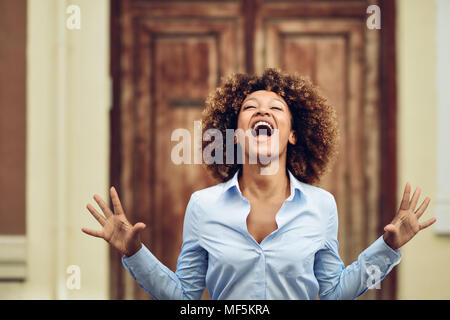 Spain, Andalusia, Malaga. Young black woman, afro hairstyle, screaming in the street. Expressions concept. Stock Photo