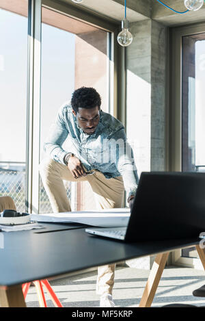 Casual businessman with laptop working on plan at table in office Stock Photo
