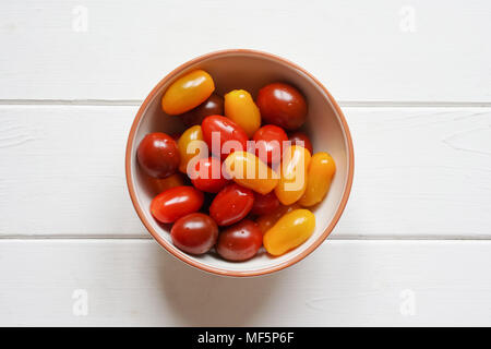 variety of organic heirloom cherry tomatoes in bowl on rustic white wooden table, overhead top view from directly above Stock Photo