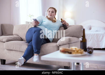 Lazy obese woman drinking beer Stock Photo