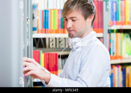 Man looking for a book in the shelf on a library Stock Photo