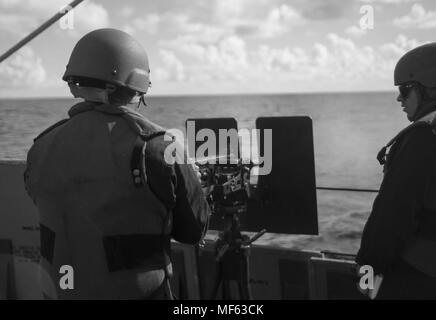 171102-N-DO281-274 ATLANTIC OCEAN (Nov. 2, 2017) Culinary Specialist 2nd Class Peter Torres fires a .50 caliber machine gun and Gunner's Mate 2nd Class Tyler Price stands Line Coach, aboard the guided-missile cruiser USS Monterey (CG 61), November 2, 2017. Monterey is deployed in support of maritime security operations in the U.S. fifth and sixth fleet area of operations (U.S. Navy photo by Mass Communication Specialist Seaman Trey Fowler). () Stock Photo