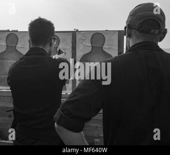 171209-N-DO281-0341 GULF OF OMAN (Dec. 9, 2017) Gunner's Mate Seaman Tyler Pilon fires a 9-millimeter pistol while Gunner's Mate 2nd Class Tyler Price stands line coach during a live fire exercise, aboard the guided-missile cruiser USS Monterey (CG 61), December 9, 2017. Monterey is deployed to the U.S. 5th Fleet area of operations in support of maritime security operations to reassure allies and partners and preserve the freedom of navigation and the free flow of commerce in the region. (U.S. Navy photo by Mass Communication Specialist Seaman Trey Fowler). () Stock Photo