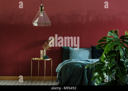 Bedroom interior with glass lamp hanging above bedside table with decorative leaf Stock Photo