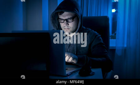 Concentrated young man working on laptop in home at night Stock Photo