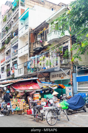 A Vietnamese woman wearing a conical hat loading bags of shopping on her bicycle in the Ton That Dam Street markets, Ho Chi Minh City, Vietnam. Stock Photo