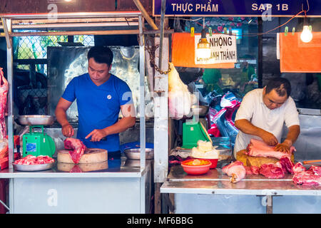 Two male butchers preparing meat in their butcher market stalls in the Ton That Dam Street markets, Ho Chi Minh City, Vietnam. Stock Photo