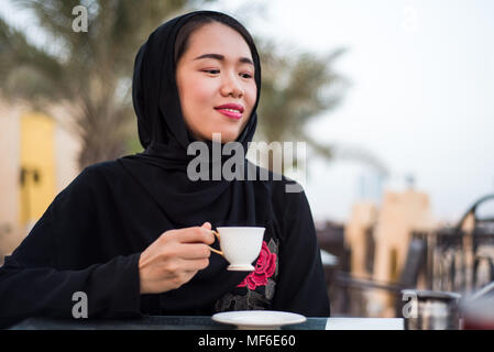 Muslim woman having a cup of coffee in a bar outdoors Stock Photo