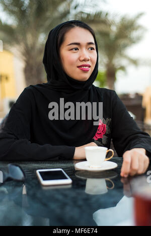 Muslim woman sitting in a coffee bar outdoors Stock Photo
