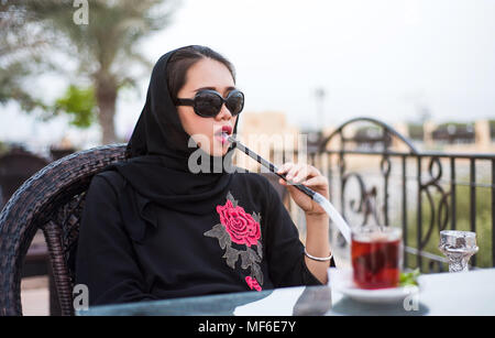 Muslim woman smoking shisha in a bar outdoors Stock Photo