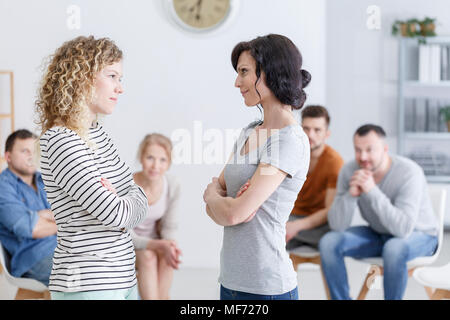 Two happy women making amends during a group psychotherapy meeting Stock Photo