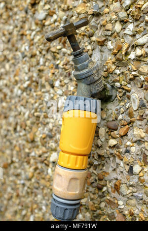 Close up of an outdoor tap attached to a pebble dashed wall. Stock Photo