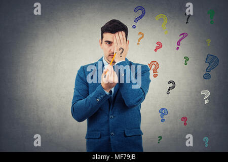 Portrait of young man hiding half face with his palm trying to draw new identity. Half face with sad, angry emotion and another one is unknown. Colorf Stock Photo