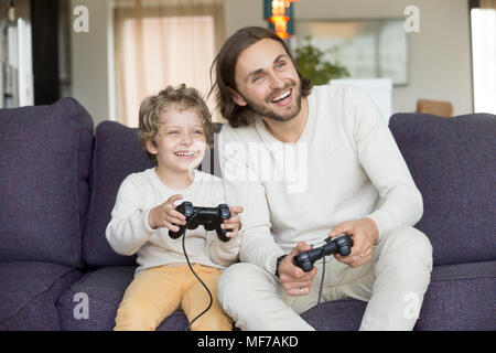 Happy dad having fun laughing playing video games with son Stock Photo