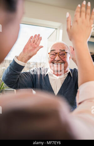 Happy senior man with raised hands looking at young woman Stock Photo