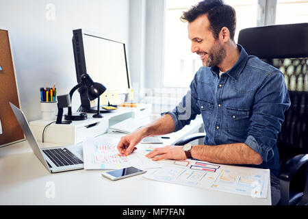 Smiling web designer working on draft at desk in office Stock Photo