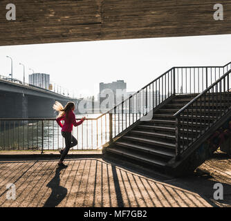 Young woman running towards stairs at a river Stock Photo