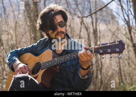 Young man playing guitar outdoors Stock Photo