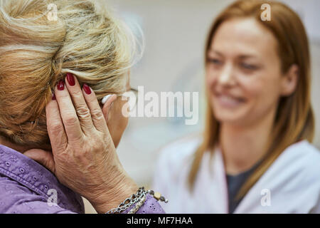 Female doctor and senior woman with hearing aid Stock Photo