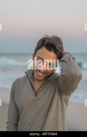 Portrait of smiling young man on the beach at twilight Stock Photo