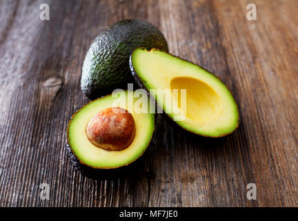 Whole and sliced avocado on wood Stock Photo