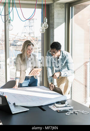 Two colleagues working on plan at table in office Stock Photo