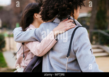 Spain, Barcelona, two women in city park embracing Stock Photo