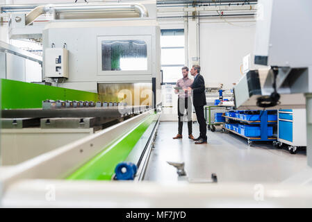 Businessmen using tablet during meeting in production hall Stock Photo