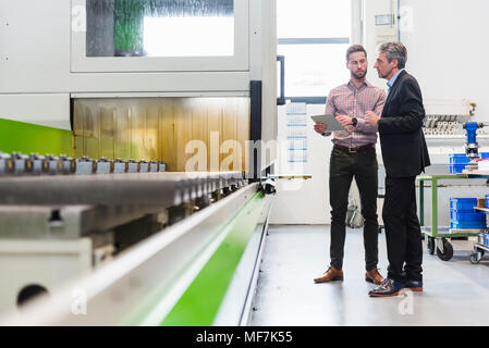 Businessmen using tablet during meeting in production hall Stock Photo