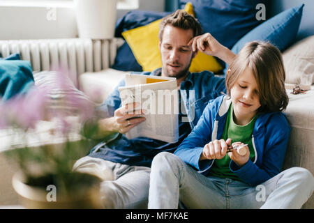 Father reading newspaper while son carving at home Stock Photo