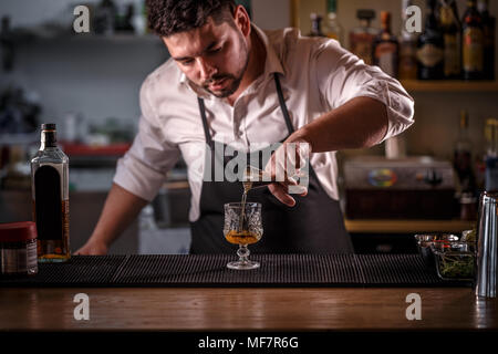 Bartender is pouring alcohol from a measuring glass into a glass Stock Photo
